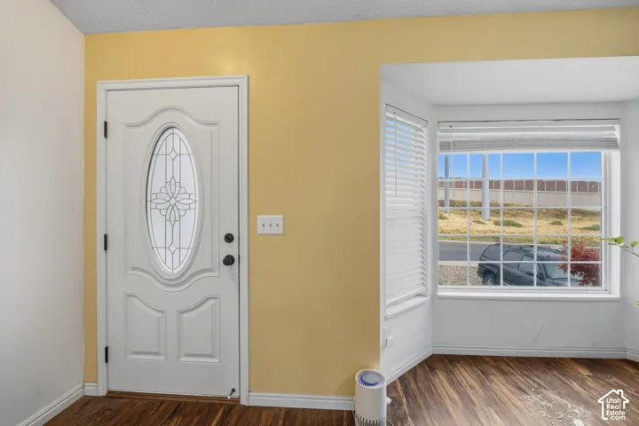 Entry area featuring a solid white door with a decorative oval glass insert, multi-pane bay window, and wood-finish flooring