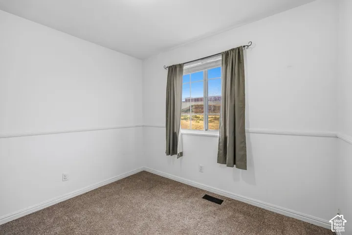 Interior room featuring neutral wall-to-wall carpeting, white walls, and decorative chair rail molding