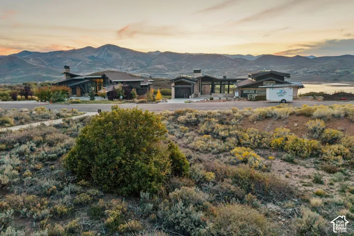 Contemporary exterior with expansive glass, multiple rooflines, a paved driveway, and a distant mountain range backdrop