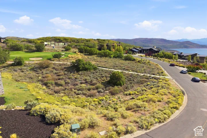 Expansive grounds featuring a manicured golf course, paved roadway, and distant body of water surrounded by mountainous terrain