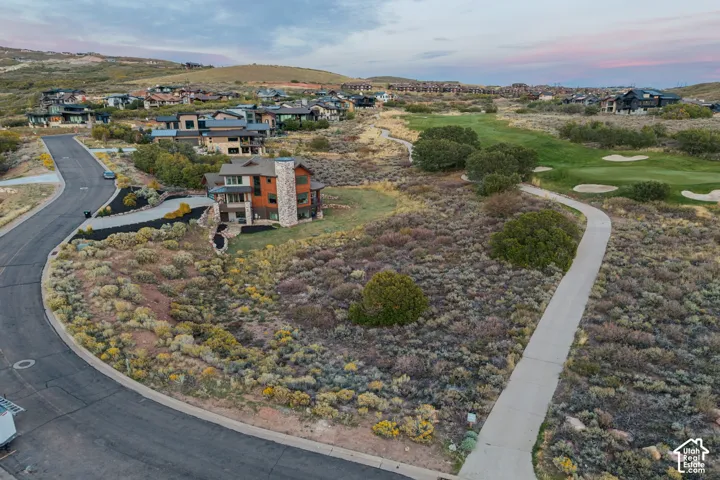 Contemporary multi-story exterior with stone and wood-tone siding, direct golf course access, extensive natural landscaping, and an integrated paved pathway