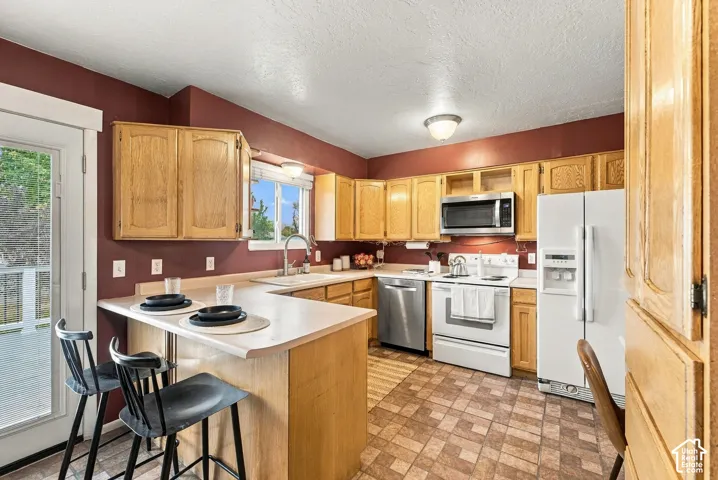 Kitchen featuring natural wood cabinetry, solid surface countertops with an integrated breakfast bar, stainless steel appliances, and tile flooring