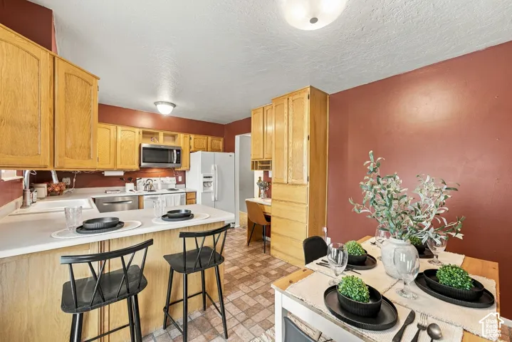 Kitchen featuring light-tone wood cabinetry, built-in microwave, integrated breakfast bar with countertop extension, and a dedicated built-in desk workspace