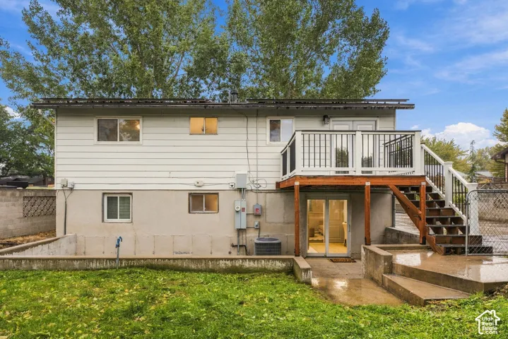 Exterior featuring white horizontal siding, an elevated wood deck with black metal railing, concrete stairs, and a concrete patio
