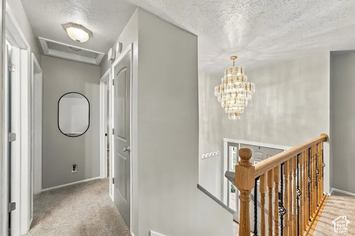 Multi-tiered crystal chandelier, staircase with wood handrail, and decorative metal balusters