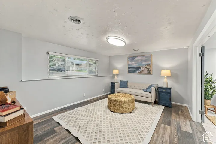 Neutral-toned interior space featuring wood-finish flooring, a large horizontal window with slatted blinds, and a modern flush-mount light fixture