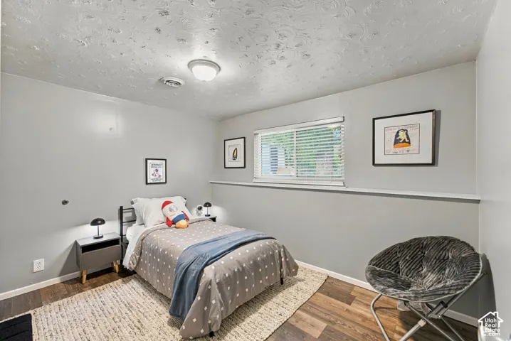 Room featuring wood-finish flooring, textured ceiling, light grey wall paint, and a horizontal window with a ledge