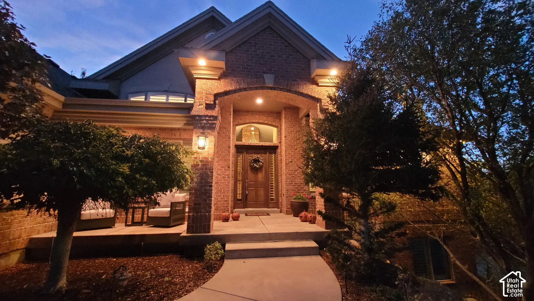 Brick exterior facade featuring a covered entryway, arched masonry detailing, transom window above the main entry, and stone-finish walkway
