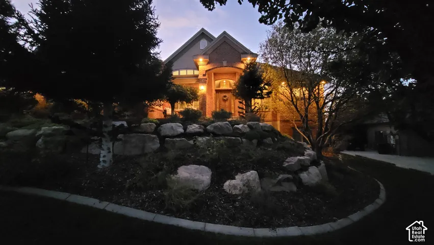 Multi-gabled exterior featuring brick masonry, a covered arched entryway, stacked stone retaining walls, and mature landscaping