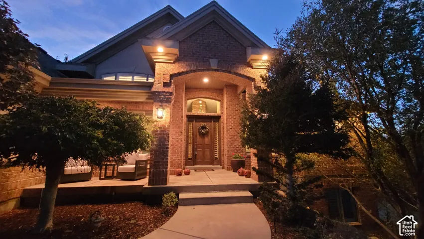 Brick exterior facade featuring a covered entryway, arched masonry detailing, transom window above the main entry, and stone-finish walkway