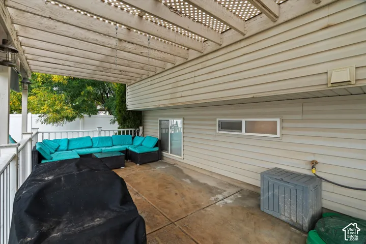 Covered patio featuring a wooden pergola, concrete flooring, horizontal vinyl siding, and white railing