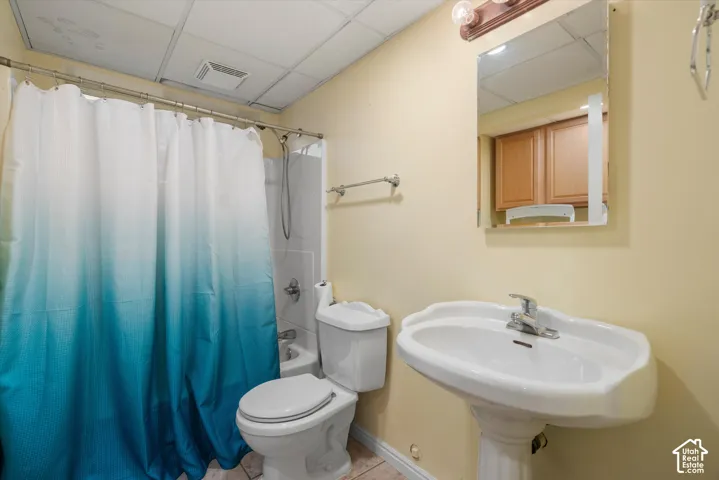 Pedestal sink with a polished chrome faucet, wall-mounted mirror, wood-finish cabinetry, and a shower-tub combination