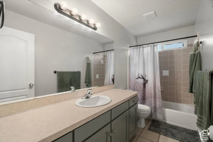 Bathroom featuring a vanity with a solid-surface countertop, an integrated sink, a full-width vanity mirror, a multi-bulb light fixture, and a tile-surround shower and tub combination