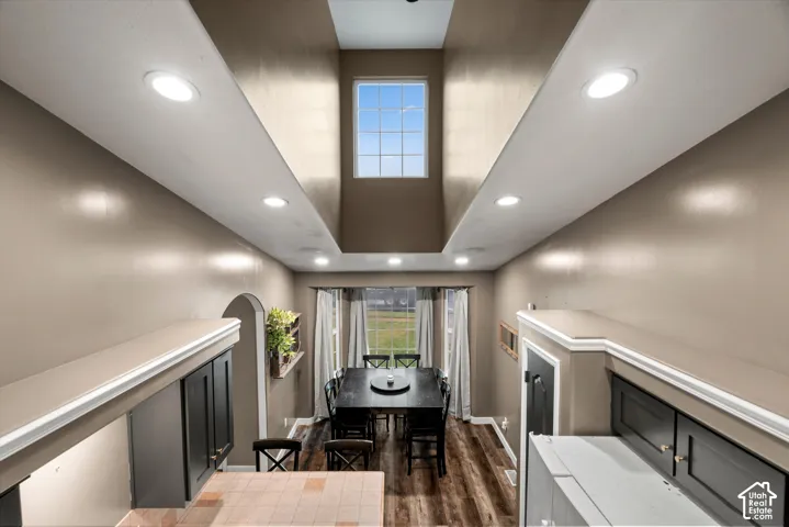 Vaulted ceiling featuring a central skylight, recessed lighting, wood-finish flooring, and a multi-pane bay window