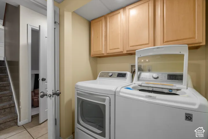 Laundry area featuring neutral-toned tile flooring and elevated wood-finish cabinetry