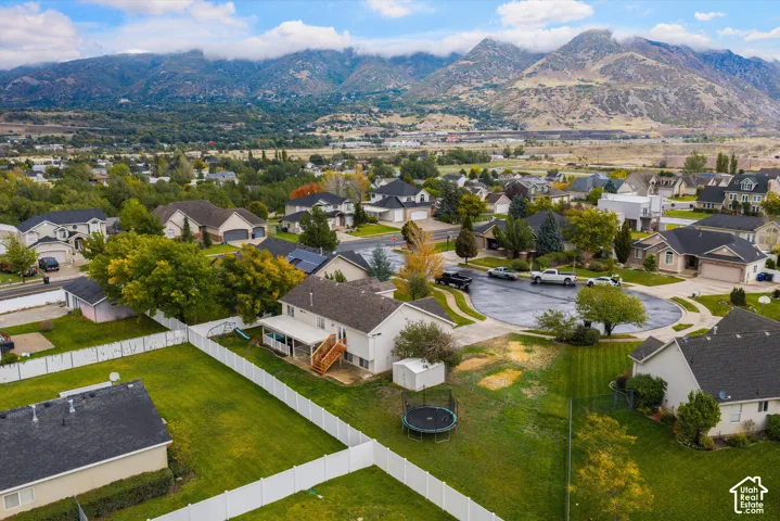 Aerial perspective featuring expansive mountain backdrops, a fenced rear yard, and a covered patio deck