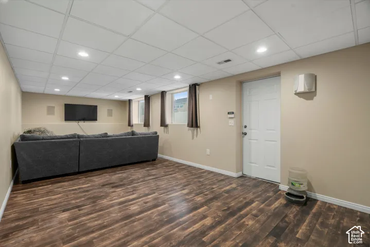 Interior room featuring wood-finish flooring, a drop ceiling with integrated recessed lighting, multiple windows, and a dedicated exterior access door