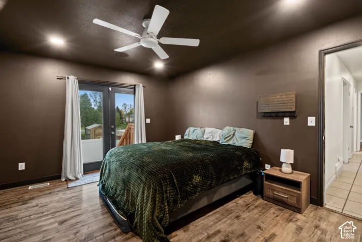 Wood-finish flooring, recessed lighting, ceiling fan, and double-glass paneled doors opening to an outdoor deck