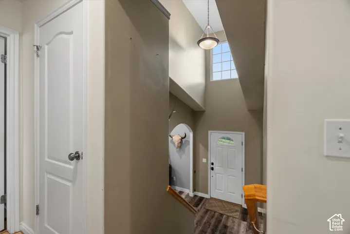 High-ceiling entryway featuring a multi-lite transom window, a dome-style pendant light, wood-finish flooring, and a arched doorway