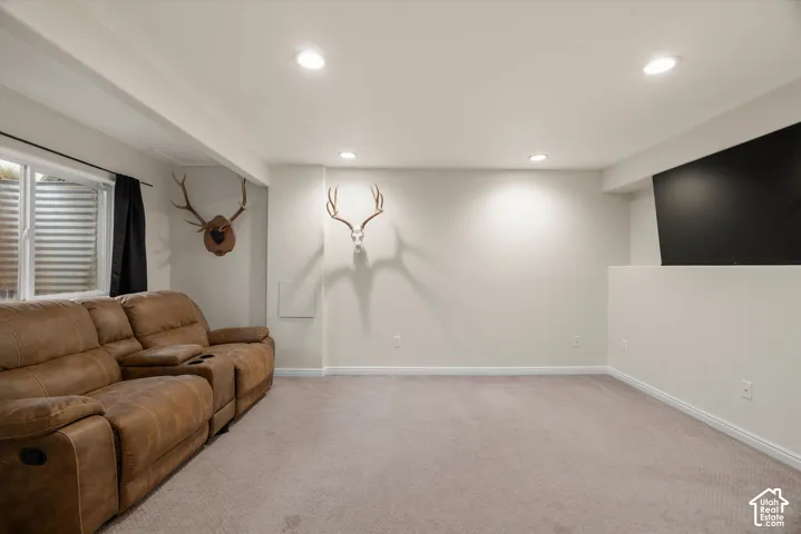 Neutral-toned room featuring recessed ceiling lighting, carpeted flooring, and a window with a window well