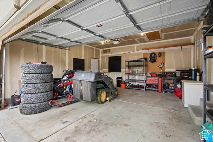Multi-car garage featuring a sectional overhead door, concrete flooring, and an attic access panel