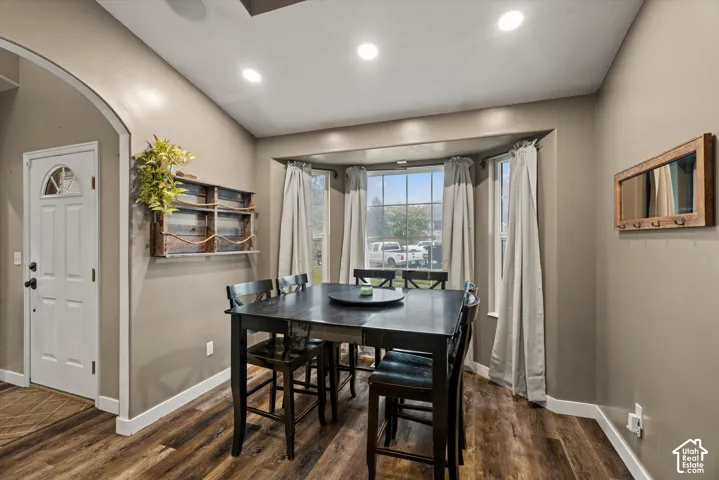 Dining area featuring wood-finish flooring, a multi-pane bay window, recessed ceiling lighting, and an arched entryway