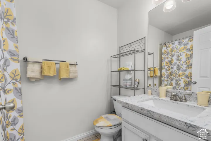 Bathroom featuring a vanity with a stone-finish countertop, undermount sink, dual-handle faucet, large wall-mounted mirror, and overhead track lighting