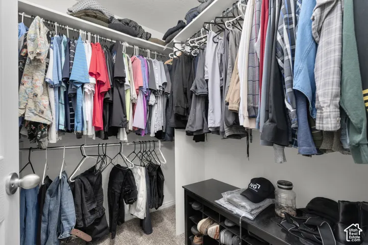 Walk-in closet featuring tiered built-in shelving and dual-level metal hanging rods