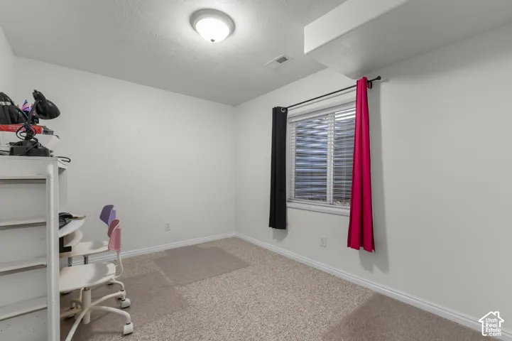 Neutral-toned interior space featuring wall-to-wall carpeting, a recessed window, and a flush-mount ceiling light fixture