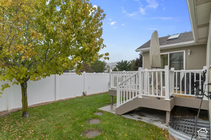 Backyard featuring a raised composite deck with white railings, a skylight, a privacy fence, and mature trees