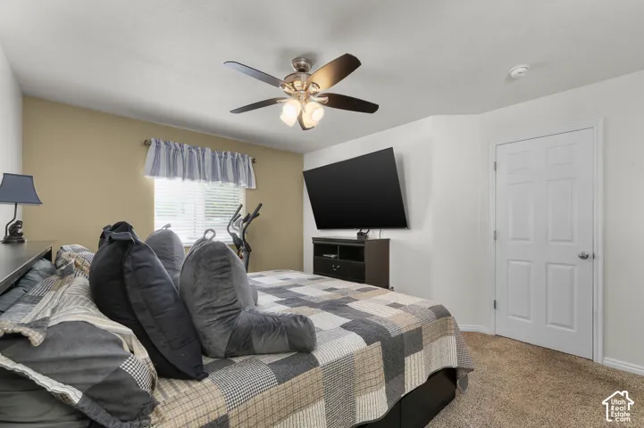 Bedroom featuring neutral wall paint, carpeting, a ceiling fan with integrated lighting, and a six-panel interior door