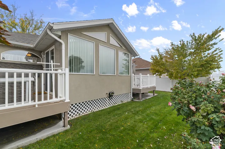 Exterior features include a stucco finish, elevated deck with white railing, built-in hot tub, lattice foundation skirting, and transom windows