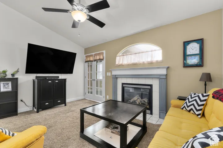 Vaulted ceilings, fireplace with tile surround and mantle, arched window, and glass-paneled french doors
