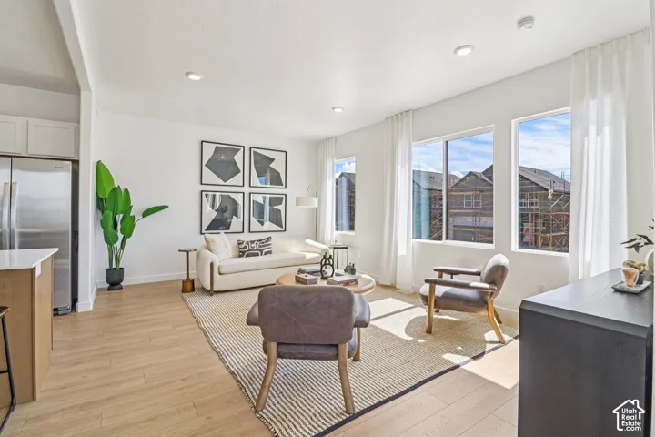 Open-concept room featuring light wood-finish flooring, recessed lighting, and large windows with natural illumination