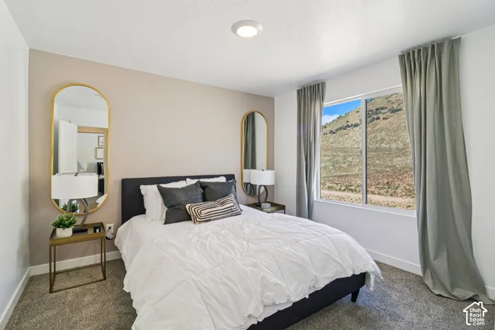 Neutral-toned bedroom featuring carpeted flooring, a recessed ceiling light, and a large window with a mountain landscape