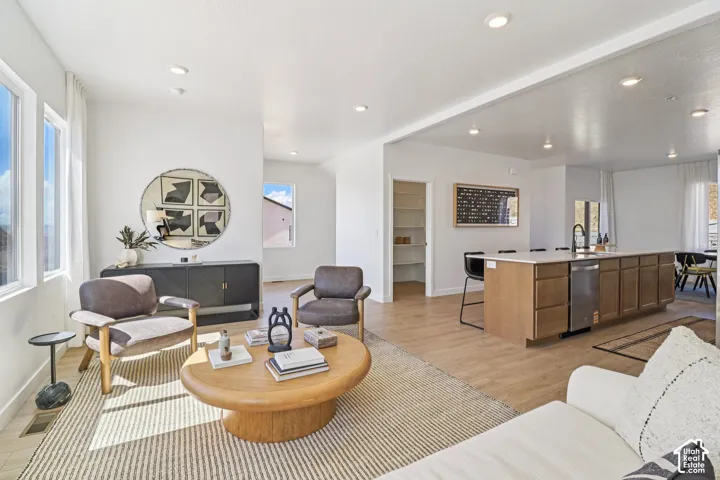Open-concept interior featuring wood-finish flooring, recessed lighting, a center island with a quartz countertop, and a walk-in pantry