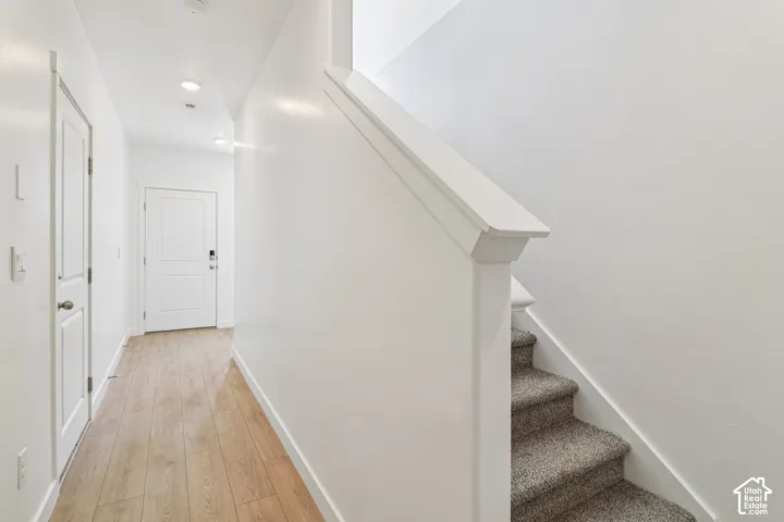 Entryway featuring wood-finish flooring, recessed lighting, and a staircase with neutral carpeting and a painted handrail
