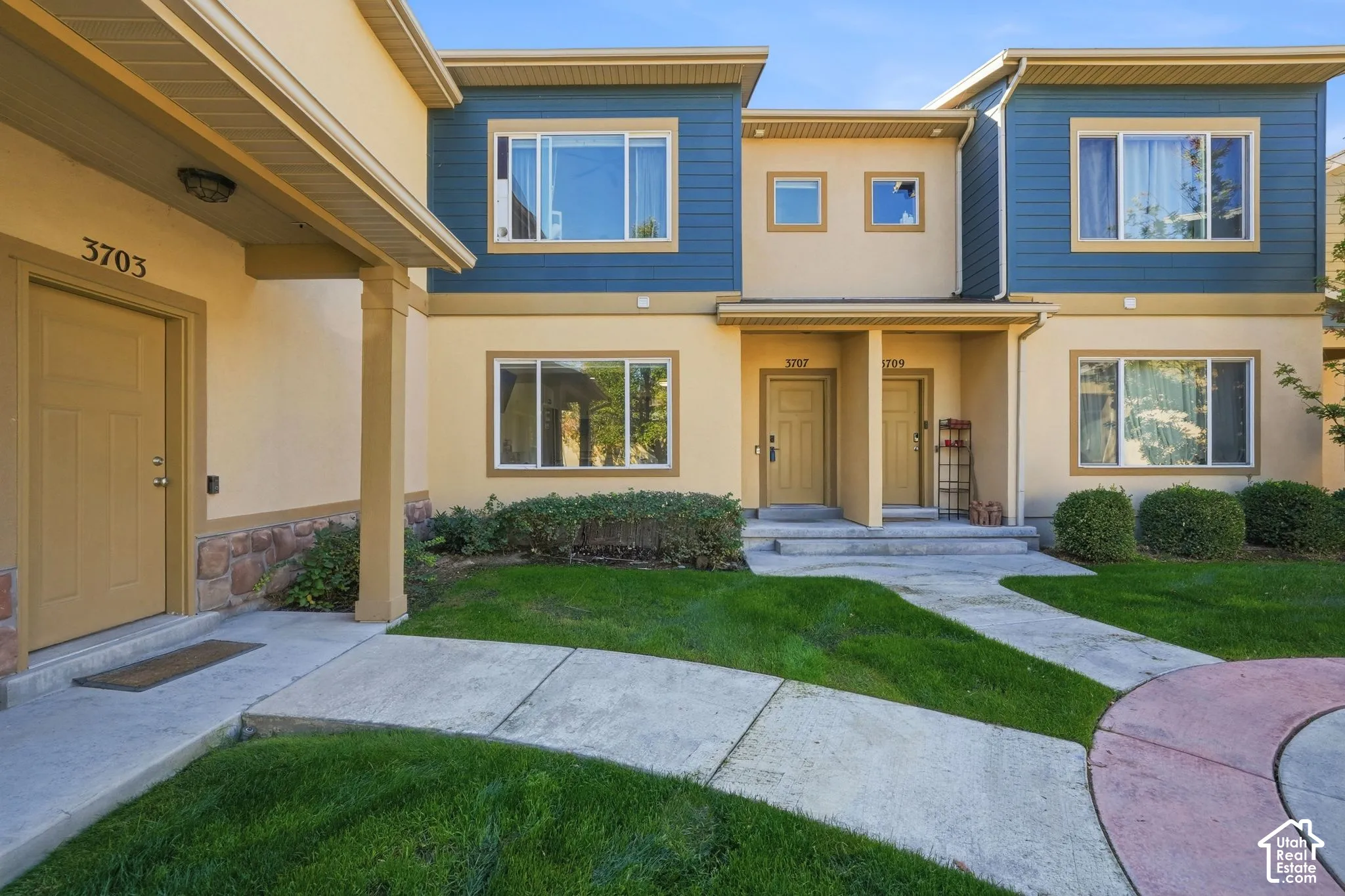 Multi-unit exterior featuring a mix of stucco and horizontal siding, covered porch entries, multi-pane windows, and stone veneer accents