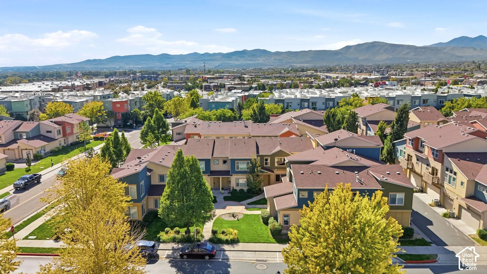 Aerial perspective of multi-family residences featuring multi-tonal siding, pitched rooflines, curated landscaping, and mountain backdrops