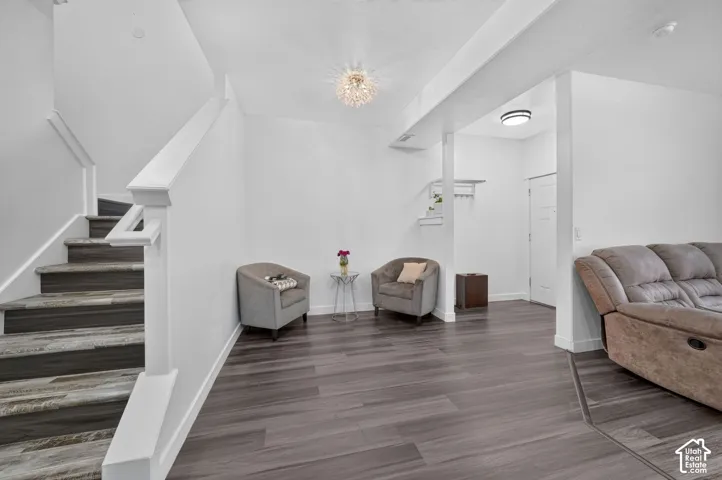 Wood-finish flooring, staircase with painted wood railings, crystal-style flush mount ceiling light, and built-in wall-mounted coat rack