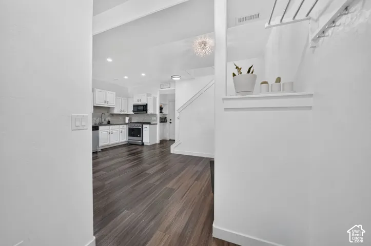 Interior space featuring wood-finish flooring, white shaker-style cabinetry, recessed lighting, and a crystal-style flush mount ceiling fixture