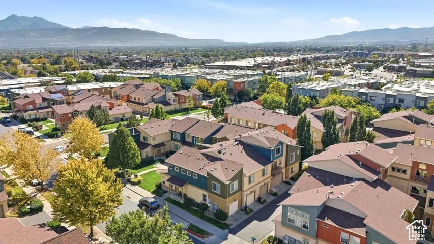 Multi-story residential exteriors featuring composite shingle roofing, integrated garage doors, and a mountain range backdrop