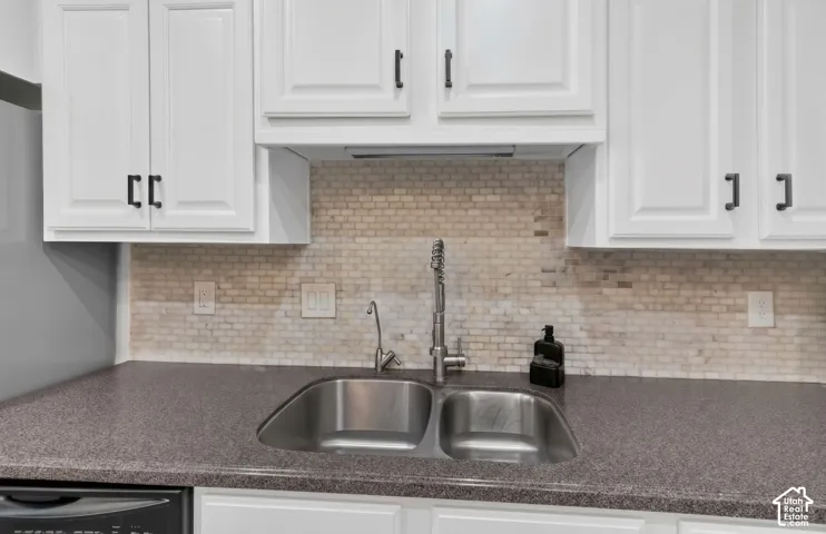 Modern kitchen featuring white shaker cabinetry, stainless steel dual-basin undermount sink, contemporary faucet with pull-down sprayer, gray quartz countertops, and a neutral brick subway tile backsplash