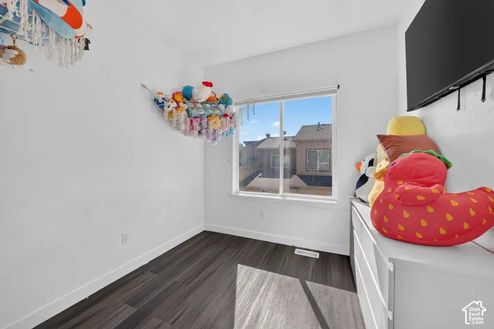 Room featuring wood-finish flooring, white walls, and a sliding window with neutral trim