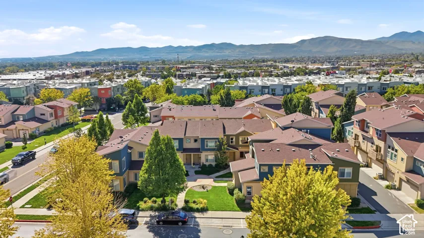 Aerial perspective of multi-family residences featuring multi-tonal siding, pitched rooflines, curated landscaping, and mountain backdrops