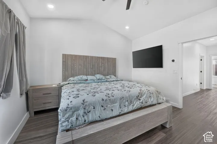 Vaulted ceilings, wood-finish flooring, integrated wood-panel headboard, recessed lighting, and a white interior sliding barn-style door