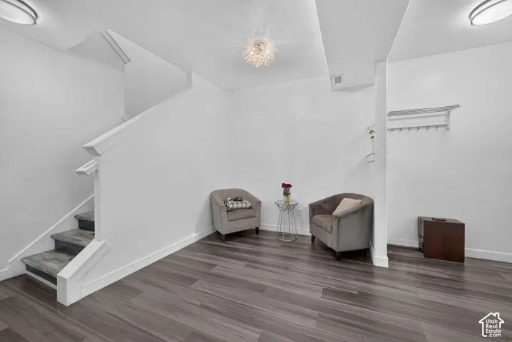 Interior area featuring wood-finish flooring, a staircase with a white balustrade, flush-mount ceiling lighting, and a wall-mounted coat rack