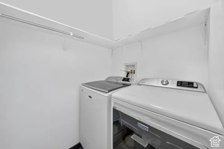 Laundry area featuring white walls, overhead shelving with a metal hanging rod, and dedicated washer and dryer hookups