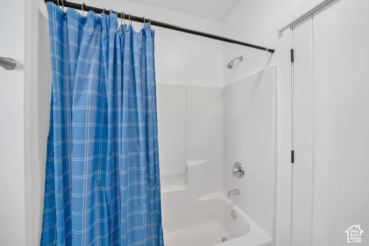 Full-height shower surround with integrated shelving, chrome-finish plumbing fixtures, and solid-core interior door with black hinges
