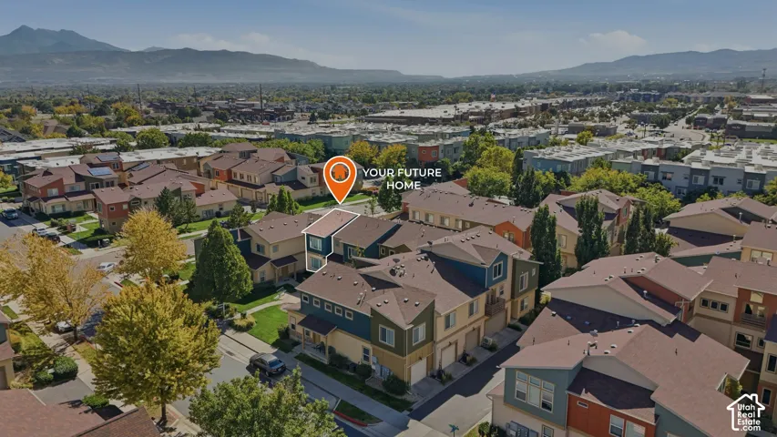 Multi-story residential property featuring a pitched roof, attached garage, and mountain range backdrop